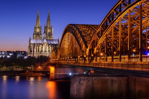 Kölner Dom und beleuchtete Hohenzollernbrücke über den Rhein bei Abenddämmerung in Köln