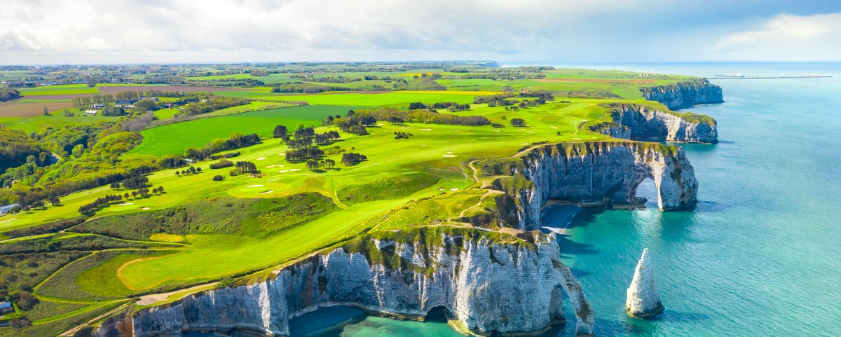 Klippen von Étretat an der französischen Küste, mit dramatischen Felsformationen und einem blauen Himmel im Hintergrund.
