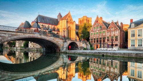 Historische Gebäude und Kanäle in Gent, Belgien, bei Sonnenuntergang, mit Spiegelungen im Wasser und einer ruhigen, malerischen Atmosphäre.
