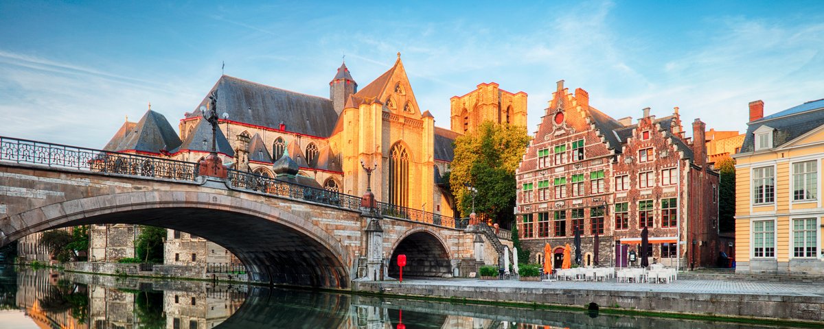 Historische Gebäude und Kanäle in Gent, Belgien, bei Sonnenuntergang, mit Spiegelungen im Wasser und einer ruhigen, malerischen Atmosphäre.