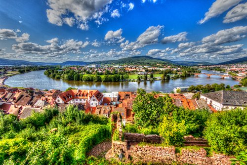 Blick auf Miltenberg mit Fachwerkhäusern und der Mainbrücke im Hintergrund, umgeben von grünen Hügeln.