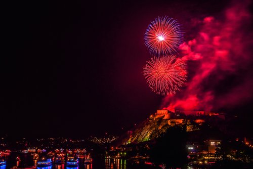 Feuerwerk erleuchtet den Nachthimmel über dem Rhein in Koblenz, während Boote auf dem Fluss fahren und Zuschauer am Ufer stehen.