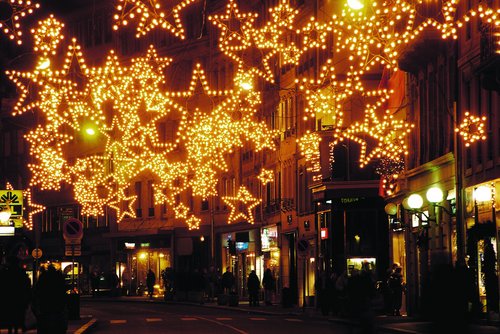 Straße bei Nacht mit zahlreichen leuchtenden Weihnachtssternen als Dekoration über der Straße.