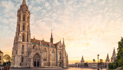 Ein beiges Kirchgebäude nahe der Fischerbastei in Budapest bei Abenddämmerung.