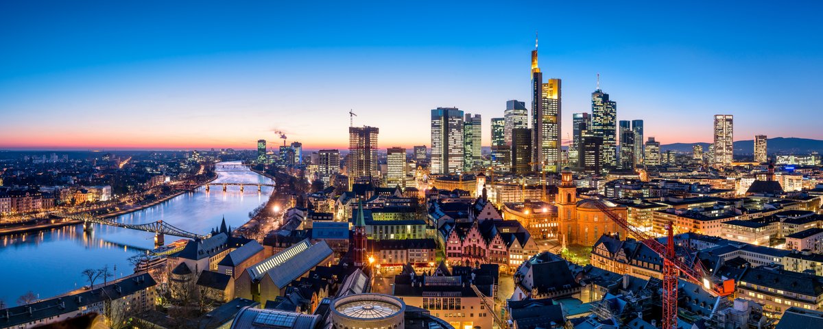 Frankfurter Skyline bei Sonnenuntergang, mit Wolkenkratzern und dem Main im Vordergrund