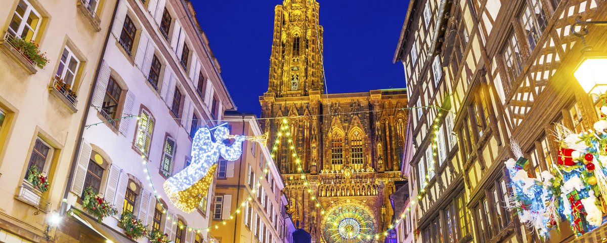 Straßburg bei Nacht mit festlich beleuchteten Häusern und einer großen Kathedrale im Hintergrund