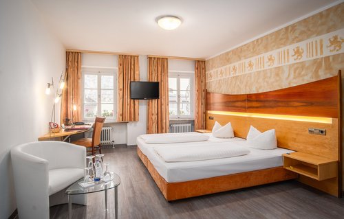 Ein Hotelzimmer mit Doppelbett, Schreibtisch und Sitzmöglichkeit im Hotel Passauer Wolf in Passau an der Donau.
