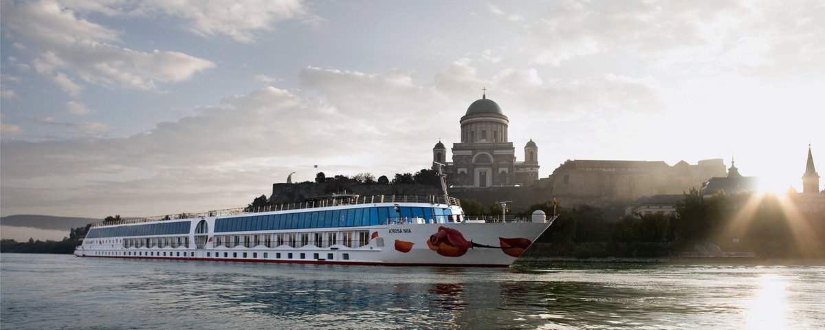 Das Flusskreuzfahrtschiff A-ROSA MIA fährt an Esztergom an der Donau mit der Sankt-Adalbert-Kathedrale bei Sonnenaufgang entlang.