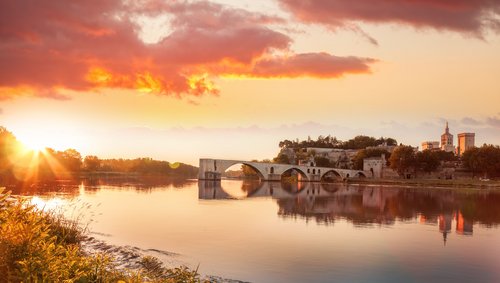 Sonnenuntergang über der historischen Brücke Pont Saint-Bénézet und der Stadt Avignon am Fluss Rhône