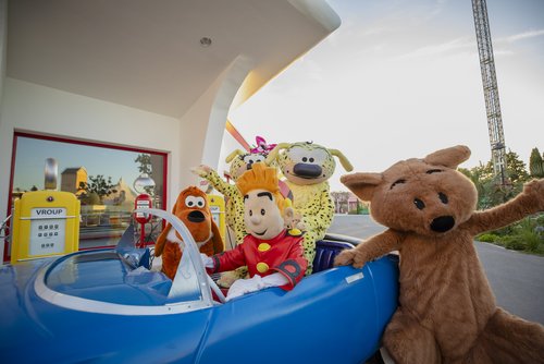 Verschiedene Maskottchen in bunten Kostümen posieren lachend im Freizeitpark Parc Spirou.