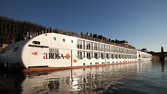 Die A-ROSA STELLA liegt am Ufer in einer Stadt an der Rhône bei Sonnenaufgang, im Hintergrund eine Brücke und Gebäude. 