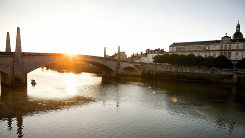 Der Blick n Ufer zum anderen in Chalon-sur-Saône mit historischen Gebäude und einer Brücke bei klarem blauem Himmel. 