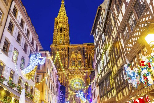 Straßburger Münster bei Nacht, umgeben von festlich beleuchteten Fachwerkhäusern und Weihnachtsdekorationen