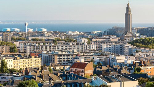 Stadtansicht von Le Havre mit dem markanten Turm der Kirche Saint-Joseph und Blick auf das Meer im Hintergrund.