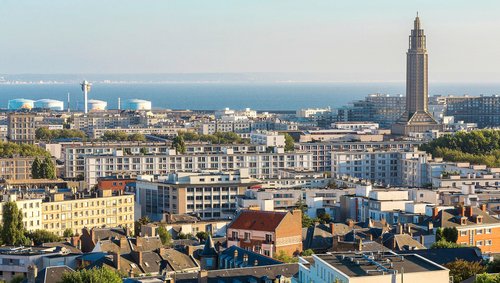 Stadtansicht von Le Havre mit dem markanten Turm der Kirche Saint-Joseph und Blick auf das Meer im Hintergrund.