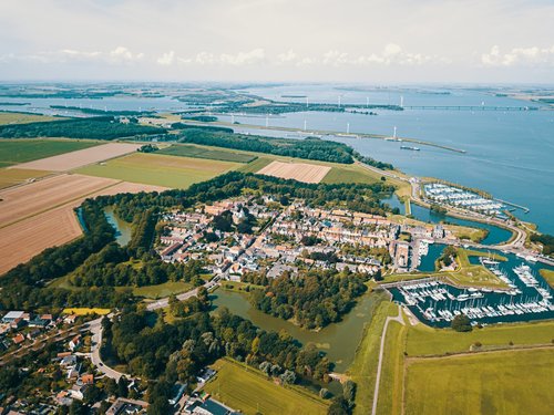 Luftaufnahme von Willemstad mit historischen Stadtmauern, umgeben von Wasser, grünen Feldern und einem Hafen mit Segelbooten