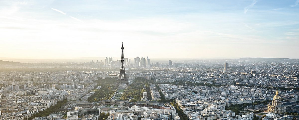 Panoramablick auf Paris mit dem Eiffelturm im Zentrum und der goldenen Kuppel der Invalidendom rechts, bei klarem Himmel. 