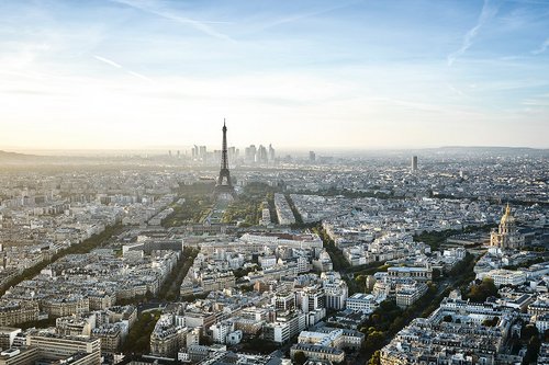 Panoramablick auf Paris mit dem Eiffelturm im Zentrum und der goldenen Kuppel der Invalidendom rechts, bei klarem Himmel. 