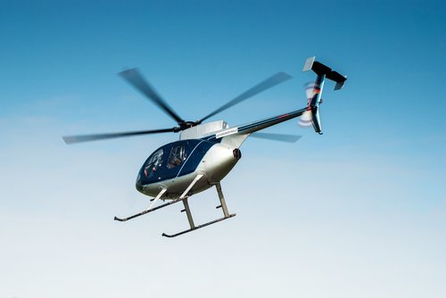 Ein blau-silberner Helikopter fliegt bei klaren, blauen Himmel 