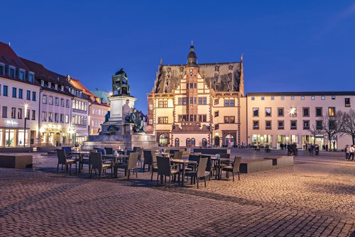 Blick auf einen Platz in Schweinfurt bei Nacht mit einem Brunnen mit Statuen im Vordergrund und historischen Gebäuden im Hintergrund