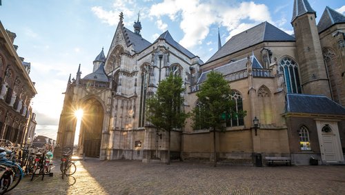 Sonnenuntergang hinter der historischen Kirche St. Stevenskerk in Nijmegen mit Kopfsteinpflaster und Fahrrädern am Straßenrand