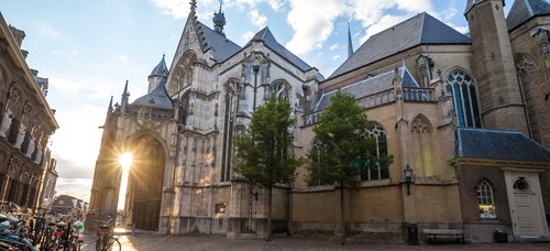 Sonnenuntergang hinter der historischen Kirche St. Stevenskerk in Nijmegen mit Kopfsteinpflaster und Fahrrädern am Straßenrand