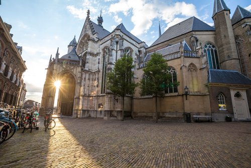 Sonnenuntergang hinter der historischen Kirche St. Stevenskerk in Nijmegen mit Kopfsteinpflaster und Fahrrädern am Straßenrand