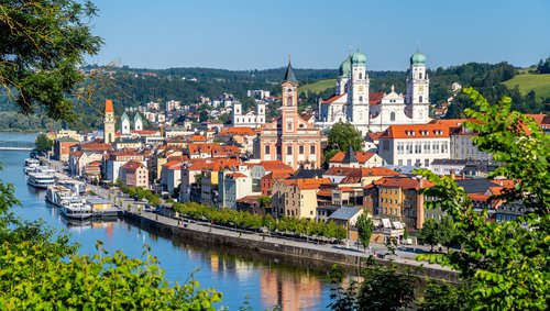 Blick auf die Altstadt von Passau mit der Donau, historischen Gebäuden und der barocken Dreifaltigkeitskirche bei klarem Himmel