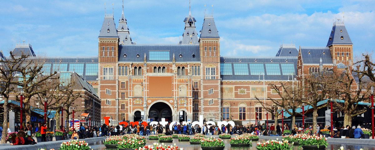 Rijksmuseum in Amsterdam mit Wasserbecken und schwimmenden Blumenarrangements im Vordergrund, Menschen vor dem Museum