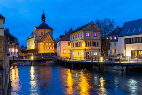 Blick auf die Altstadt von Bamberg im Herbst, mit historischen Gebäuden entlang eines Flusses bei Nacht