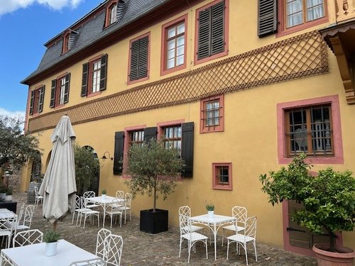 Das Weingut Allendorf mit Sitzmöglichkeiten im Vordergrund. An der Fassade sind charmante Fensterläden angebracht.