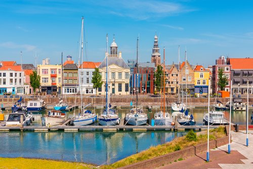 Marina in Vlissingen mit mehreren dockenden Segelbooten bei blauem Himmel. Im Hintergrund die historischen Gebäude der Stadt