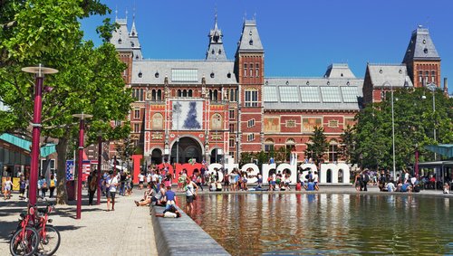 Rijksmuseum in Amsterdam mit Wasserbecken und Menschen vor dem Museum