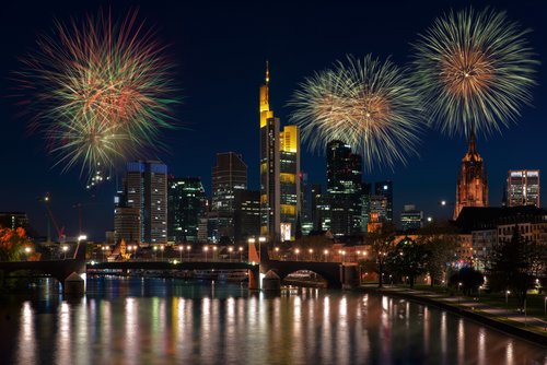 Feuerwerk erleuchtet den Nachthimmel über der Skyline von Frankfurt am Main, mit beleuchteten Wolkenkratzern im Vordergrund.