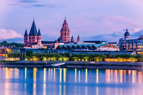 Blick auf die Mainzer Altstadt mit dem Dom und historischen Türmen bei Abendlicht, reflektiert im Rhein