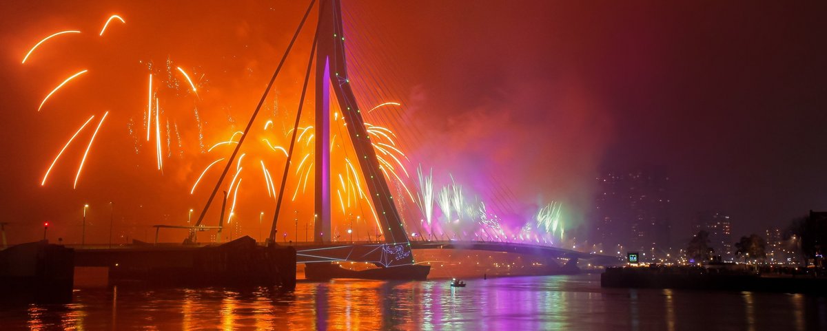 Die Erasmusbrücke in Rotterdam mit einem bunten Feuerwerk über der Brücke bei Nacht.