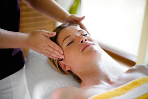 Eine Frau liegt entspannt auf einer Massageliege im SPA-ROSA, während sie eine Gesichtsmassage erhält.