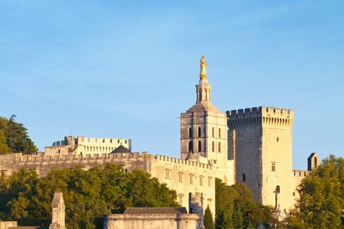 Avignon mit der berühmten Brücke Saint-Bénézet über die Rhône, im Hintergrund die historische Altstadt und der Papstpalast bei Sonnenuntergang.