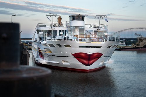 Die A-ROSA SENA mit Kussmund und Rose um Bug liegt am Abend am Anleger in einem Hafen, der Himmel ist leicht bewölkt.