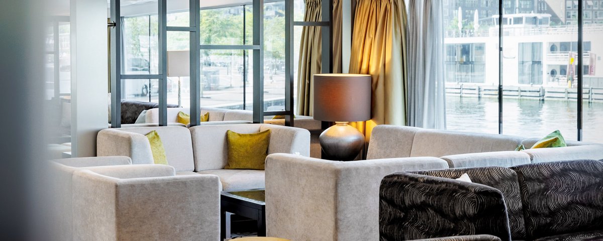 Die stilvoll eingerichtete Panoramalounge der A-ROSA CLEA mit großen, bodentiefen Fenstern, modernen Sitzmöbeln und Blick auf den Fluss.