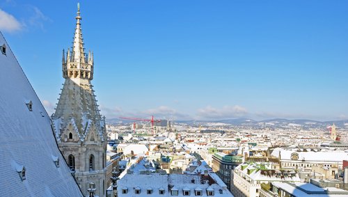 Blick über Wien mit verschneiten Dächern und dem gotischen Turm des Stephansdoms bei klarem Himmel