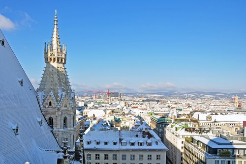 Blick über Wien mit verschneiten Dächern und dem gotischen Turm des Stephansdoms bei klarem Himmel