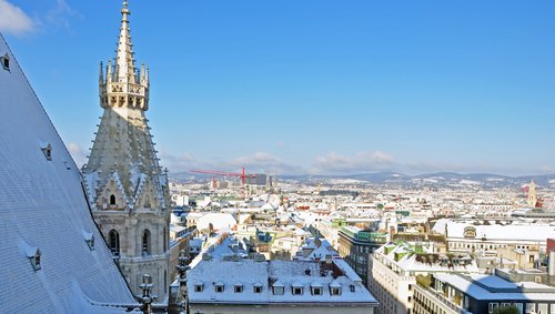 Blick über Wien mit verschneiten Dächern und dem gotischen Turm des Stephansdoms bei klarem Himmel