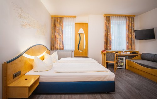 Ein Hotelzimmer mit Doppelbett, Schreibtisch und Sitzmöglichkeit im Hotel Atrium Garni in Passau an der Donau.