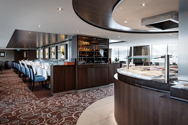 Stilvoll eingedeckter Restaurant- und Buffetbereich der A-ROSA CLEA mit Fenstern, Blumendeko und gedämpfter Beleuchtung.