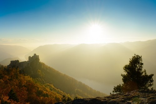 Sonnenaufgang über der herbstlichen Landschaft der Wachau mit Burgruine auf einem Hügel und Nebel im Tal