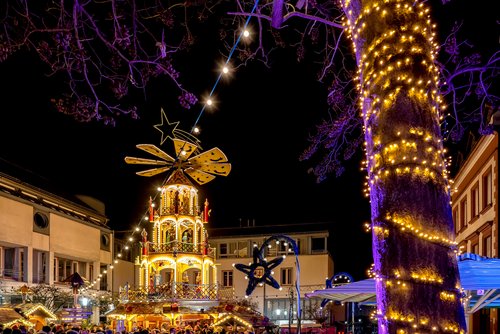 Weihnachtlich geschmückter Marktplatz in Aschaffenburg bei Nacht, mit beleuchteten Ständen und einer großen Weihnachtspyramide im Zentrum.