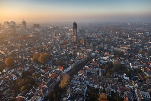 Luftaufnahme von Utrecht bei Sonnenaufgang mit dem Domturm als zentralem Wahrzeichen und dicht bebauten historischen Gebäuden
