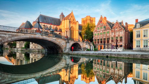 Historische Gebäude und Kanäle in Gent, Belgien, bei Sonnenuntergang, mit Spiegelungen im Wasser und einer ruhigen, malerischen Atmosphäre.