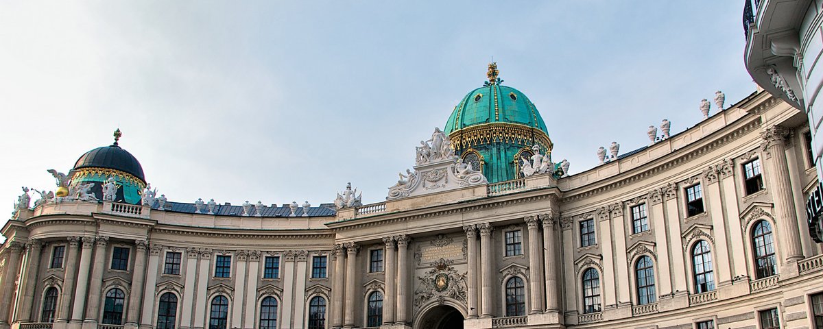 Die Hofburg in Wien mit ihrer markanten Kuppel und vielen Menschen auf dem Platz davor.